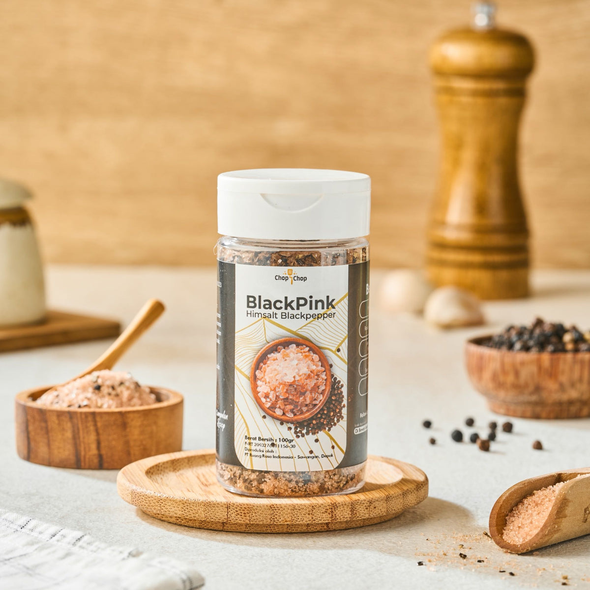 Botol BlackPink Himsalt Black Pepper di atas tatakan kayu dengan garam pink dan lada hitam