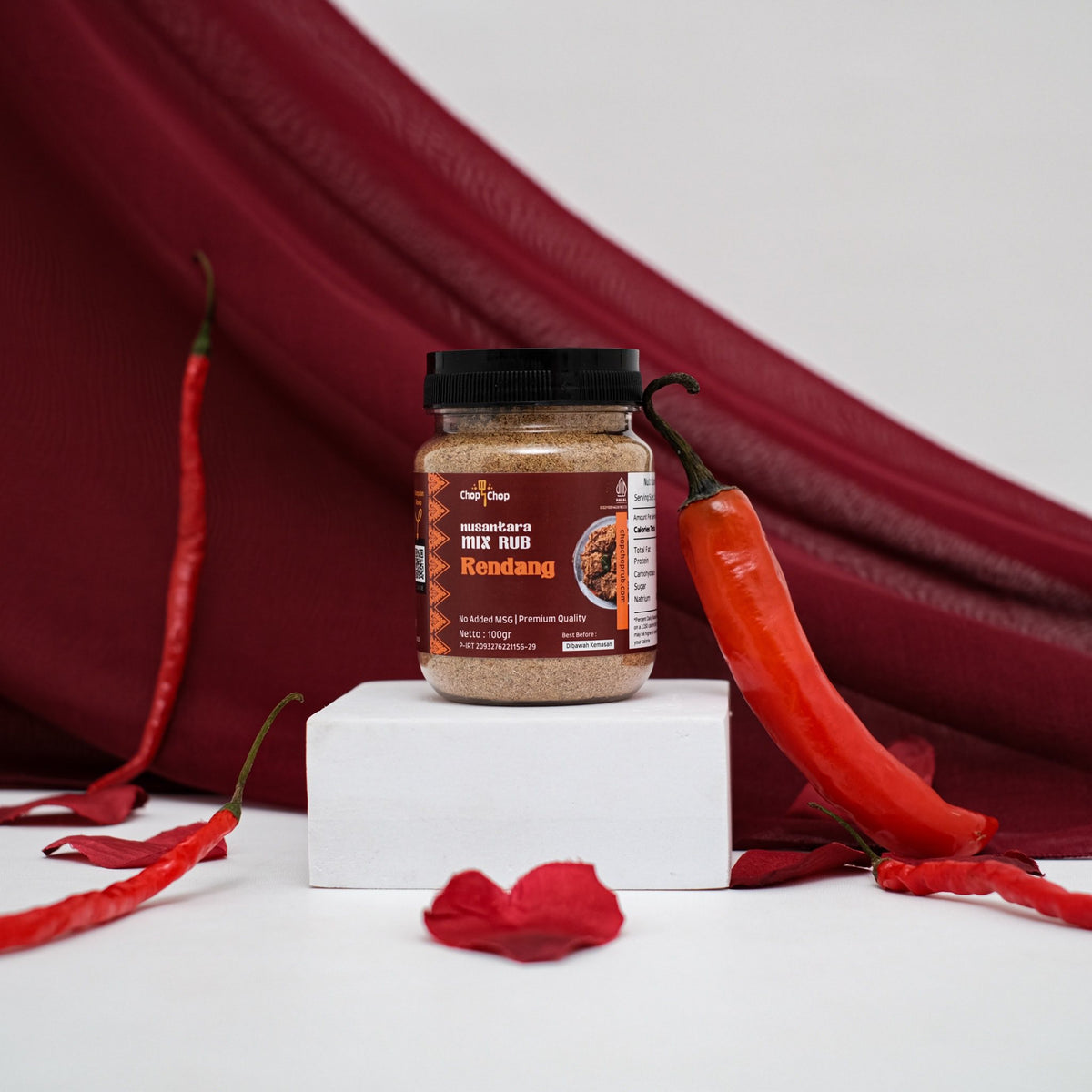 Jar Rendang Nusantara Mix Rub 100 gram di atas podium putih dengan cabai merah dan kain merah marun