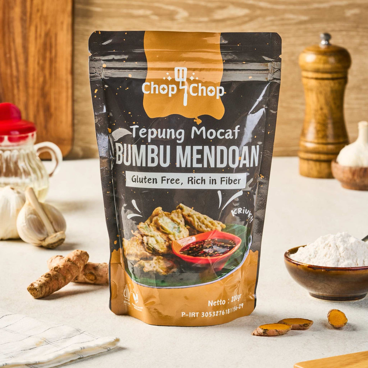 Pouch Tepung Mocaf Bumbu Mendoan 200 gram di meja dapur dengan bawang putih dan kunyit