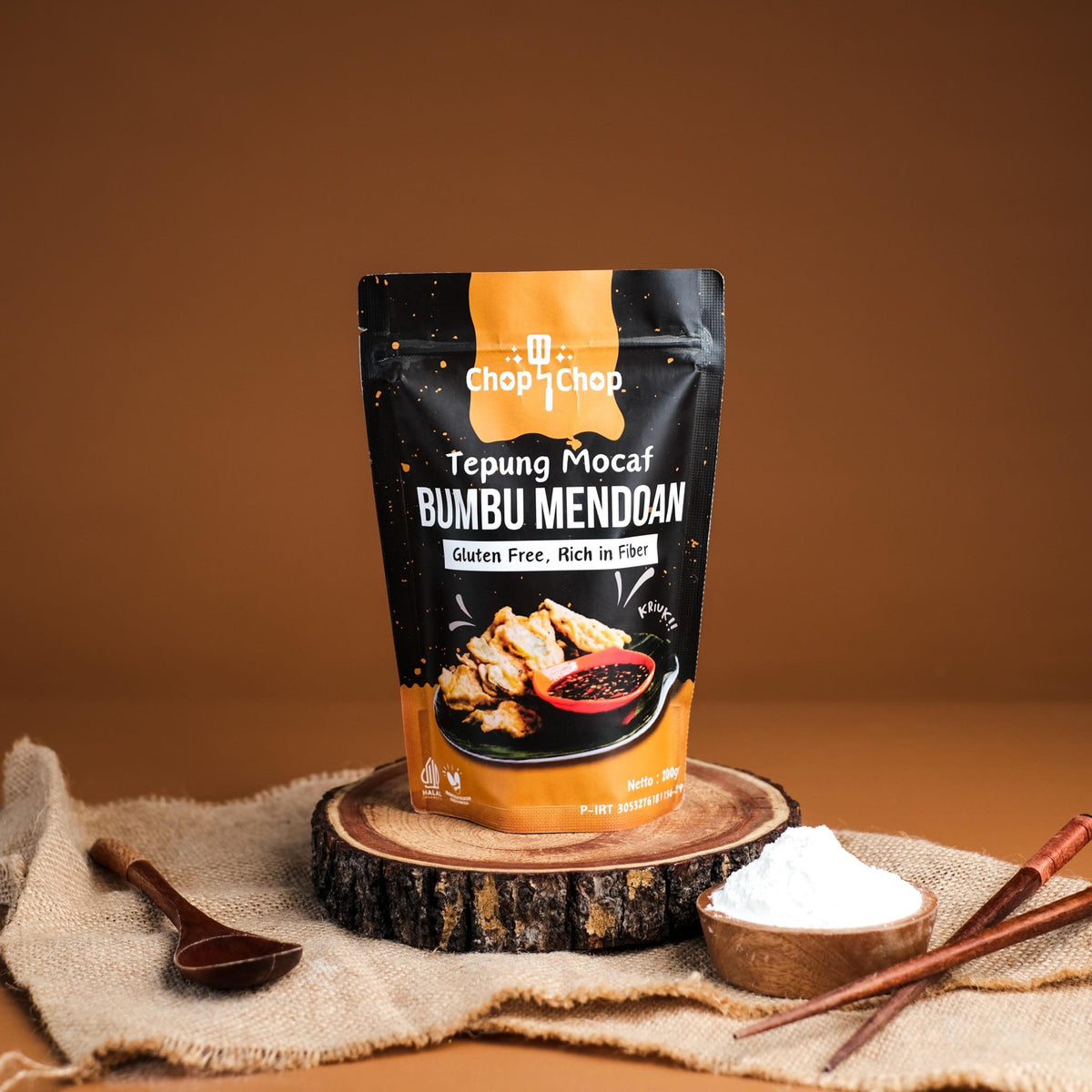 Pouch Tepung Mocaf Bumbu Mendoan di atas potongan kayu dan kain goni dengan mangkuk tepung