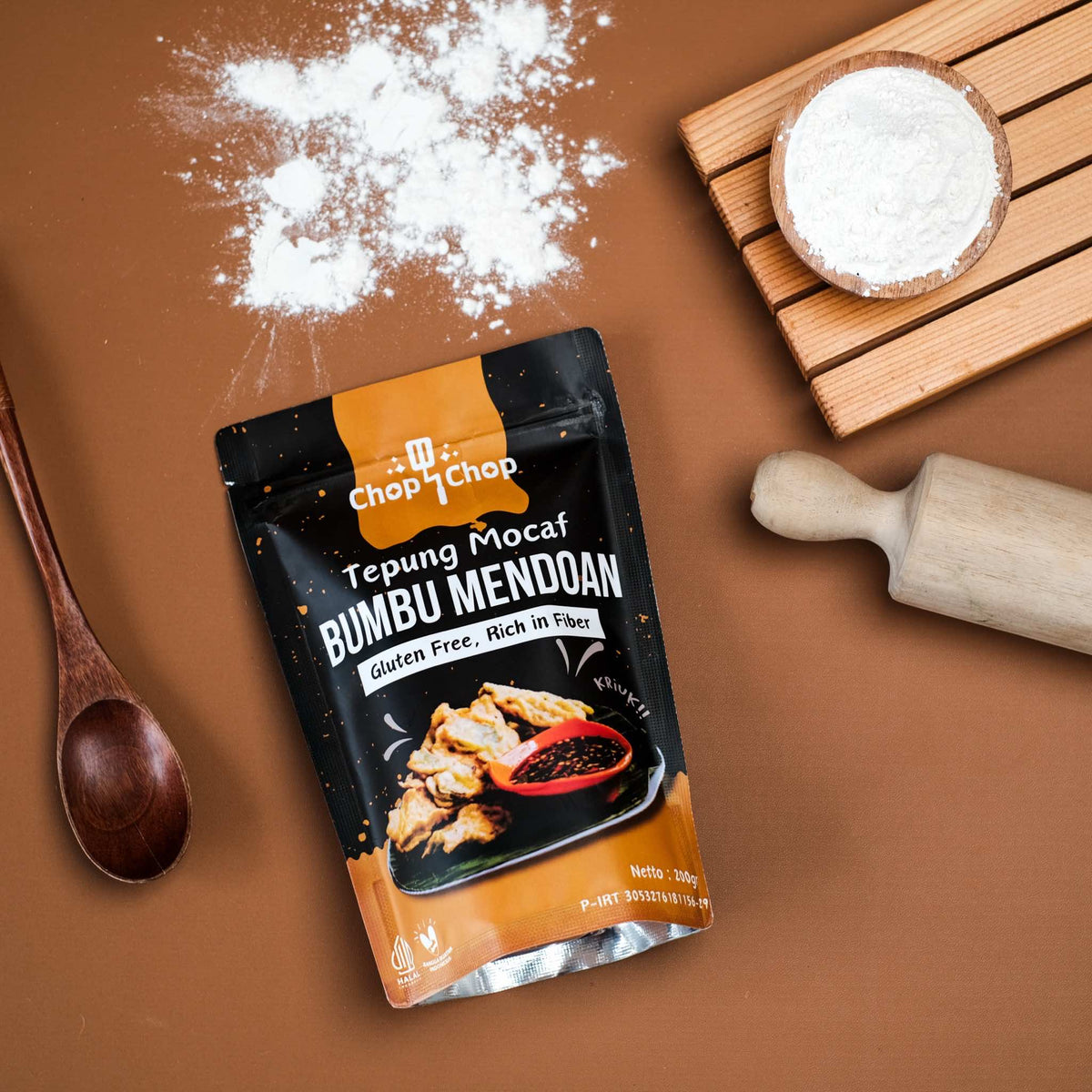 Pouch Tepung Mocaf Bumbu Mendoan dengan rolling pin, sendok kayu, dan tepung tertabur, tampak dari atas